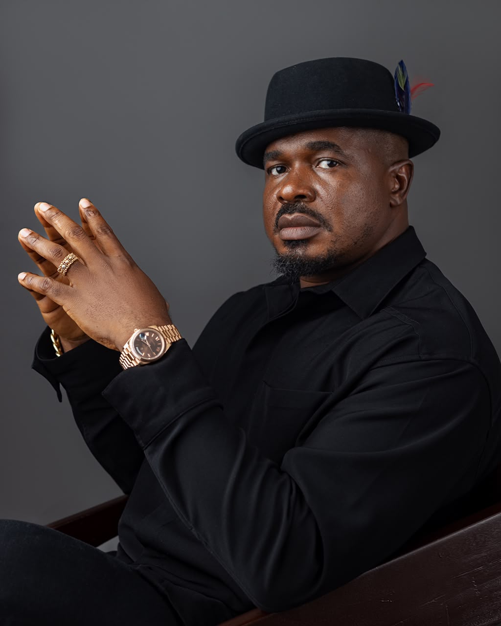 Portrait of John Ifere in a black shirt and fedora